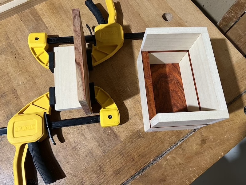 The box lid in clamps next to the assembled caracass.