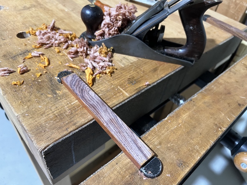 A pen blank mounted on the bench with a freshley planed face.