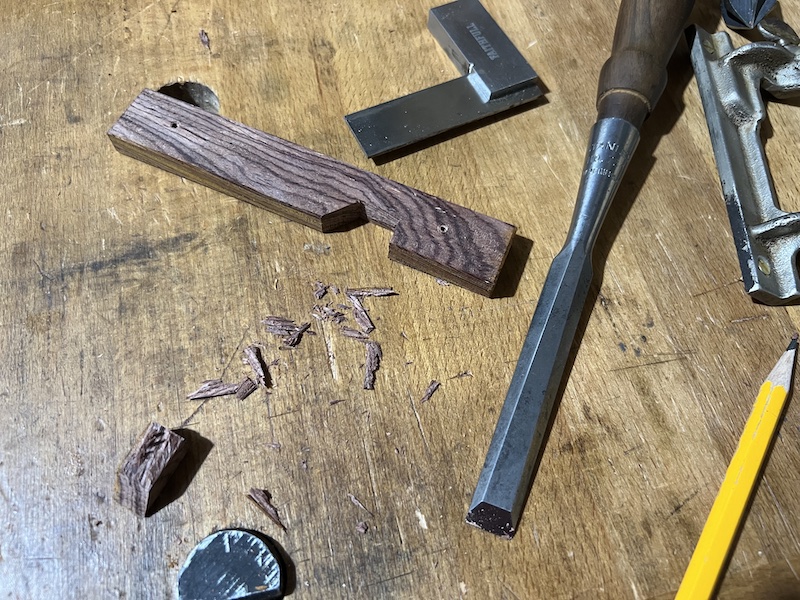 A chisel and pen fence on the workbench.  A notch has been chiseled out of the fence.