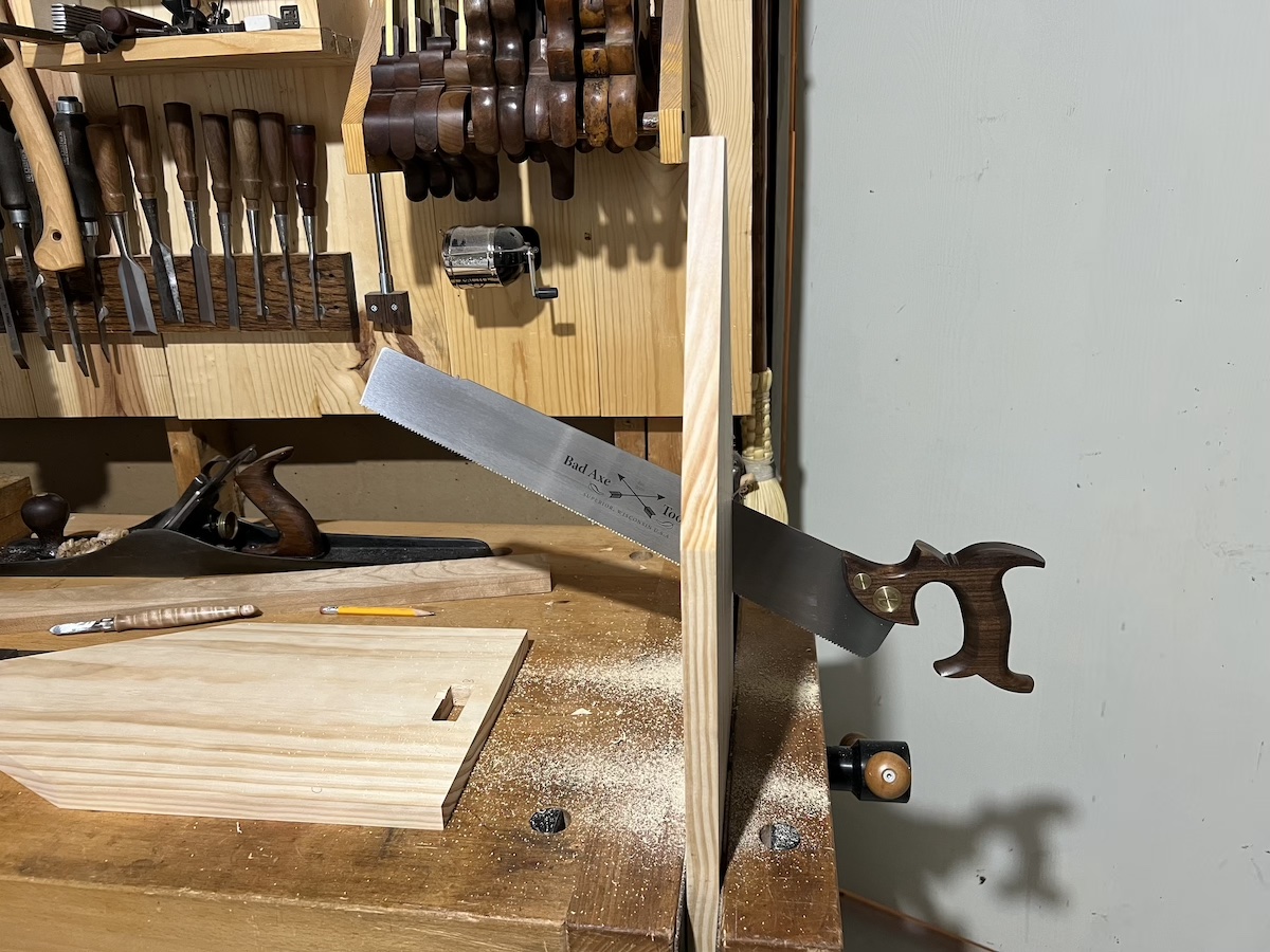 A saw cutting the wooden end vertically to make a ledge to rest a side on.